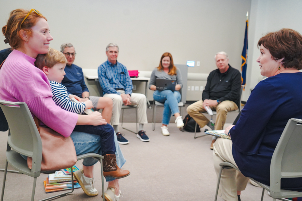 Char Fitzwater listening to a parent and child at a community meeting